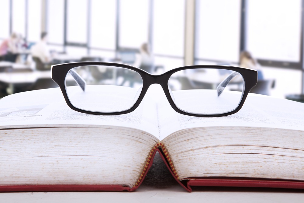 Photo of an open book with glasses on it in an academic setting